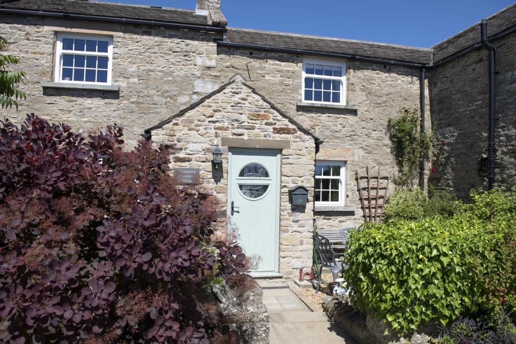 an old stone house with a white door at Theaked Stones in Leyburn
