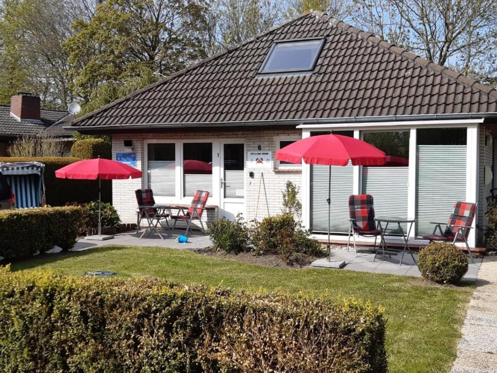 a house with red umbrellas and a table and chairs at Ferienhaus große Krabbe in Neuharlingersiel