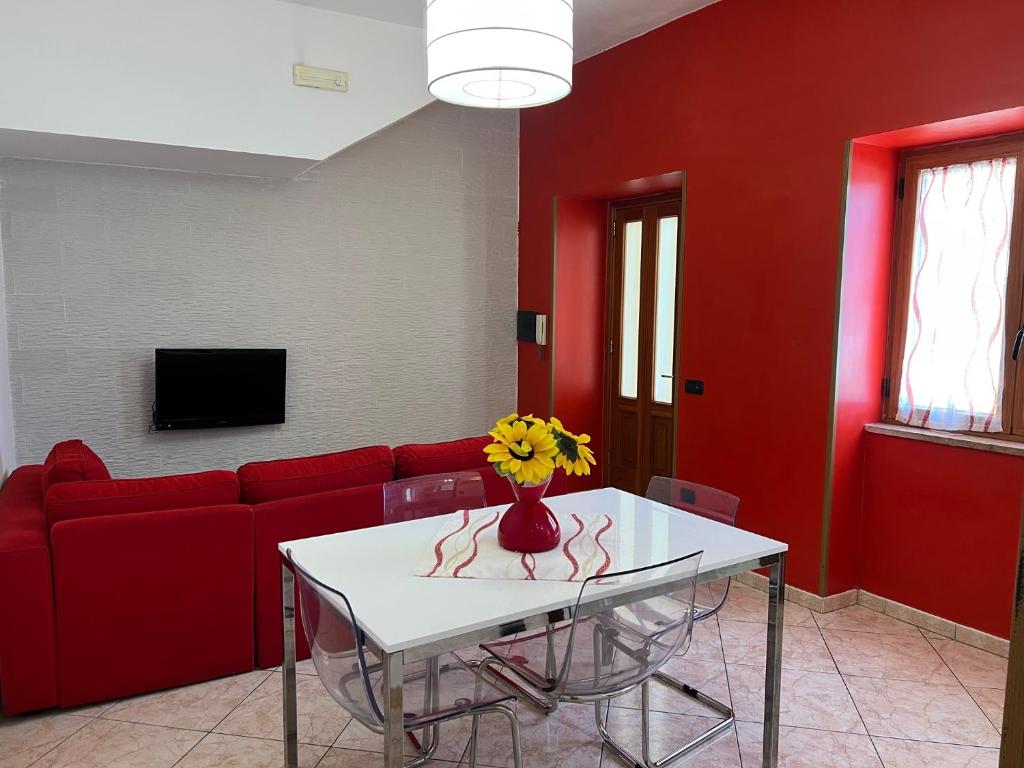 uma sala de estar com um sofá vermelho e uma mesa com flores em Villa Bebe' em Vico Equense