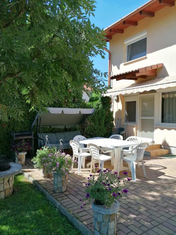 a patio with a table and chairs in a yard at Rose Vip Apartman in Hajdúszoboszló