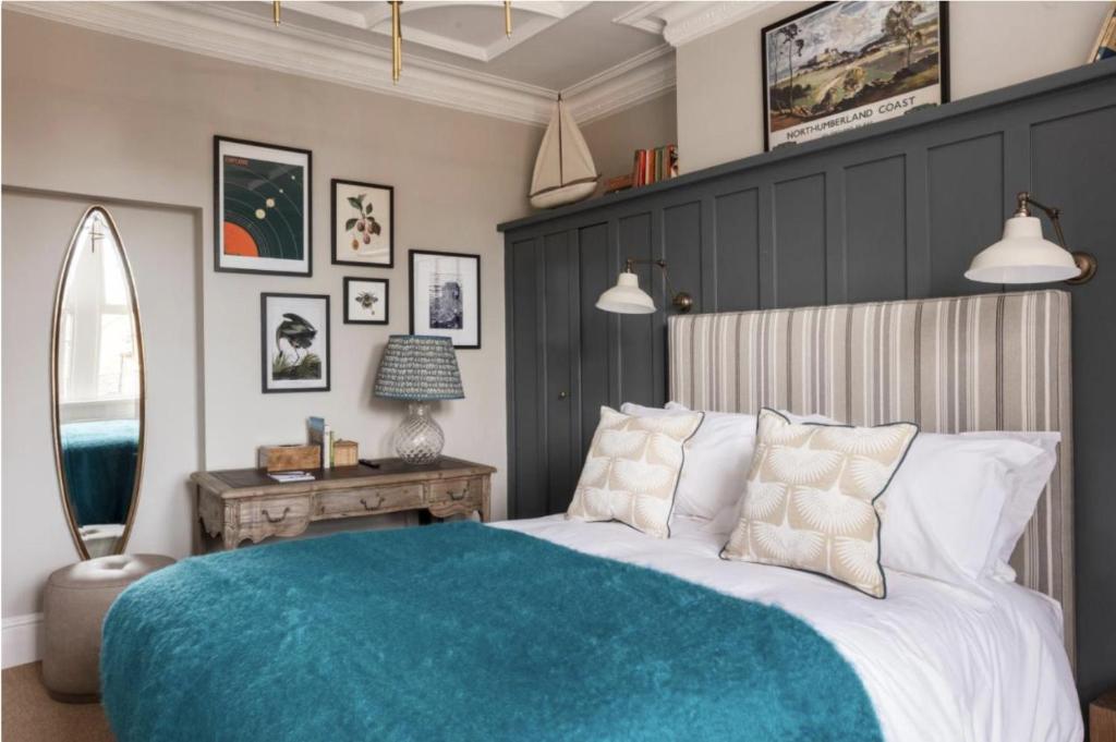 a bedroom with a large bed with a blue blanket at The Whittling House in Alnmouth