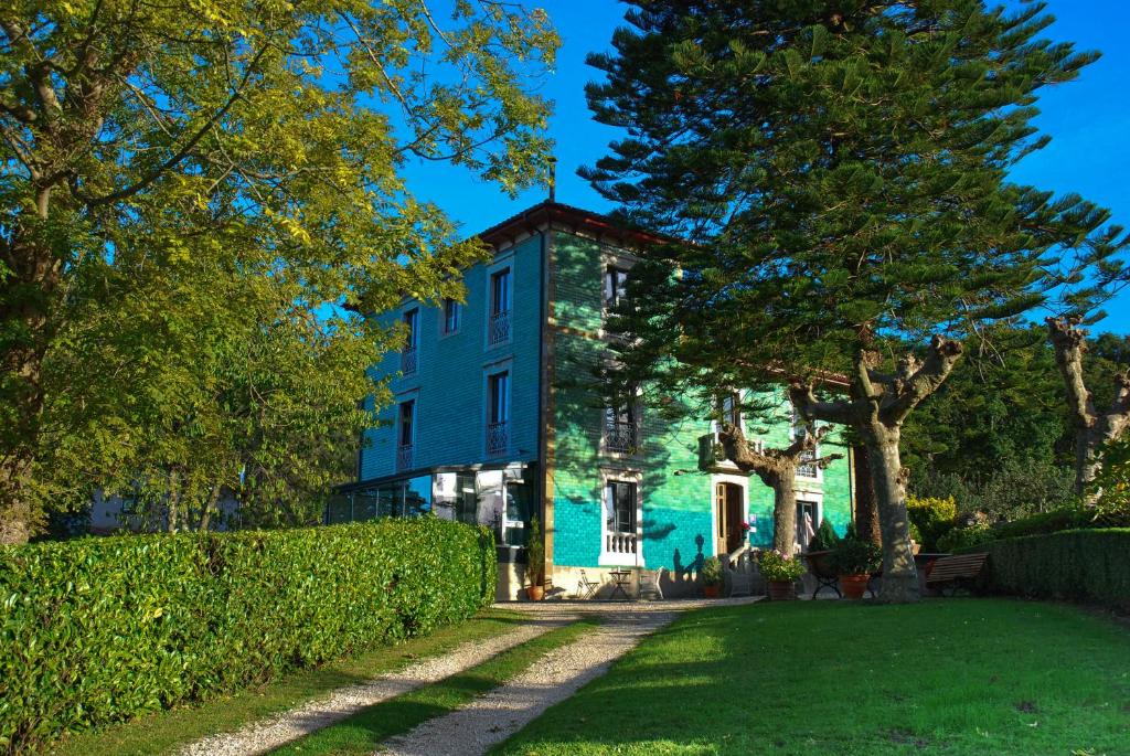 una casa blu con degli alberi di fronte di Hotel Rural La Raposera a Caravia