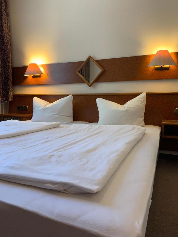 a large white bed with white sheets and pillows at Hotel Plovdiv in Berlin