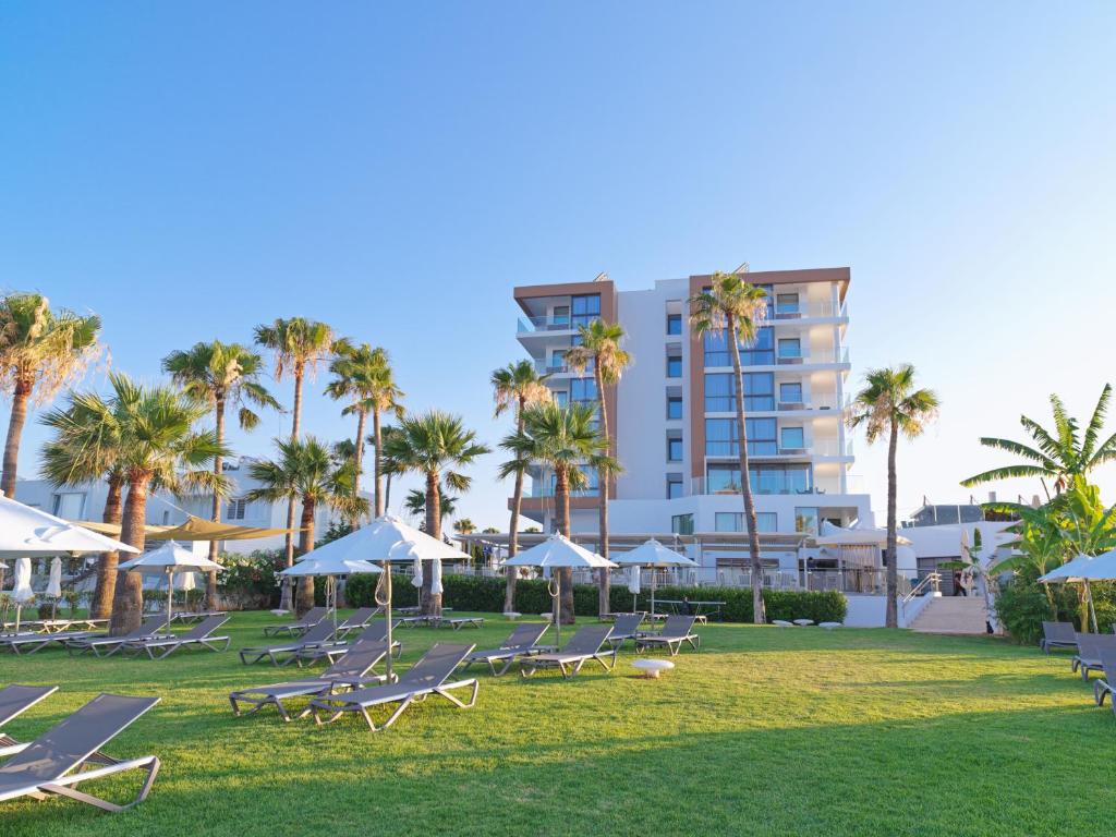 um grupo de espreguiçadeiras e palmeiras num parque em Leonardo Crystal Cove Hotel & Spa – Adults only em Protaras