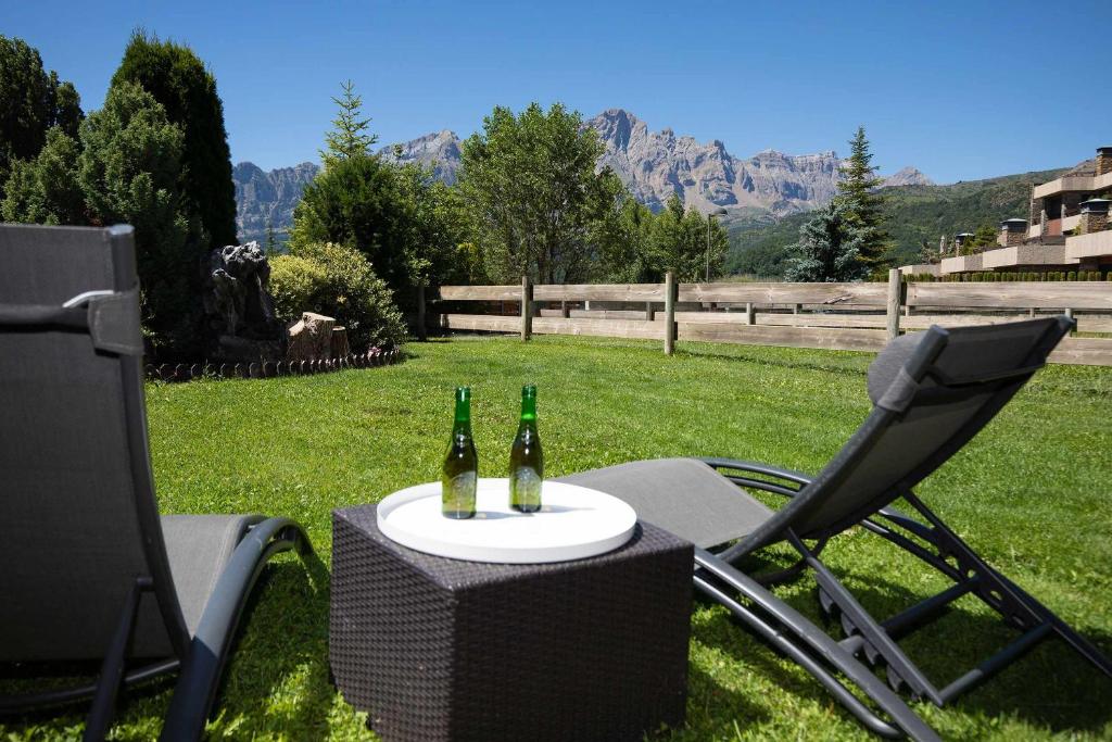 dos botellas de cerveza en una mesa con dos sillas en Jardín de Saras by BeValle, en Panticosa