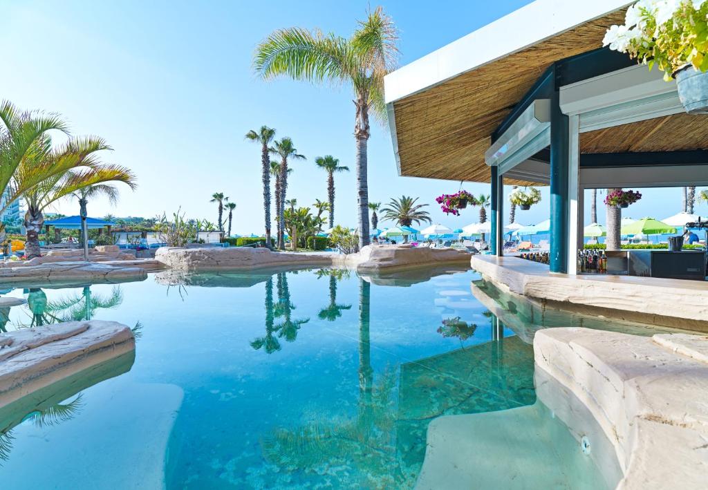 a swimming pool at a resort with palm trees at Leonardo Cypria Bay in Paphos