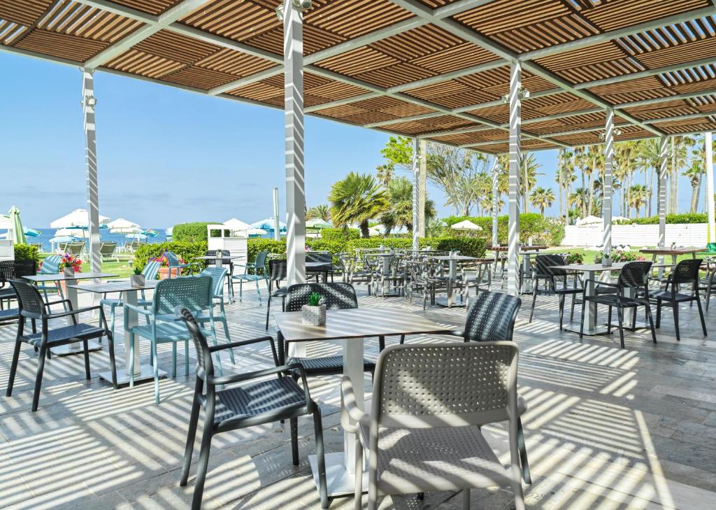 a patio with tables and chairs under a roof at Leonardo Cypria Bay in Paphos