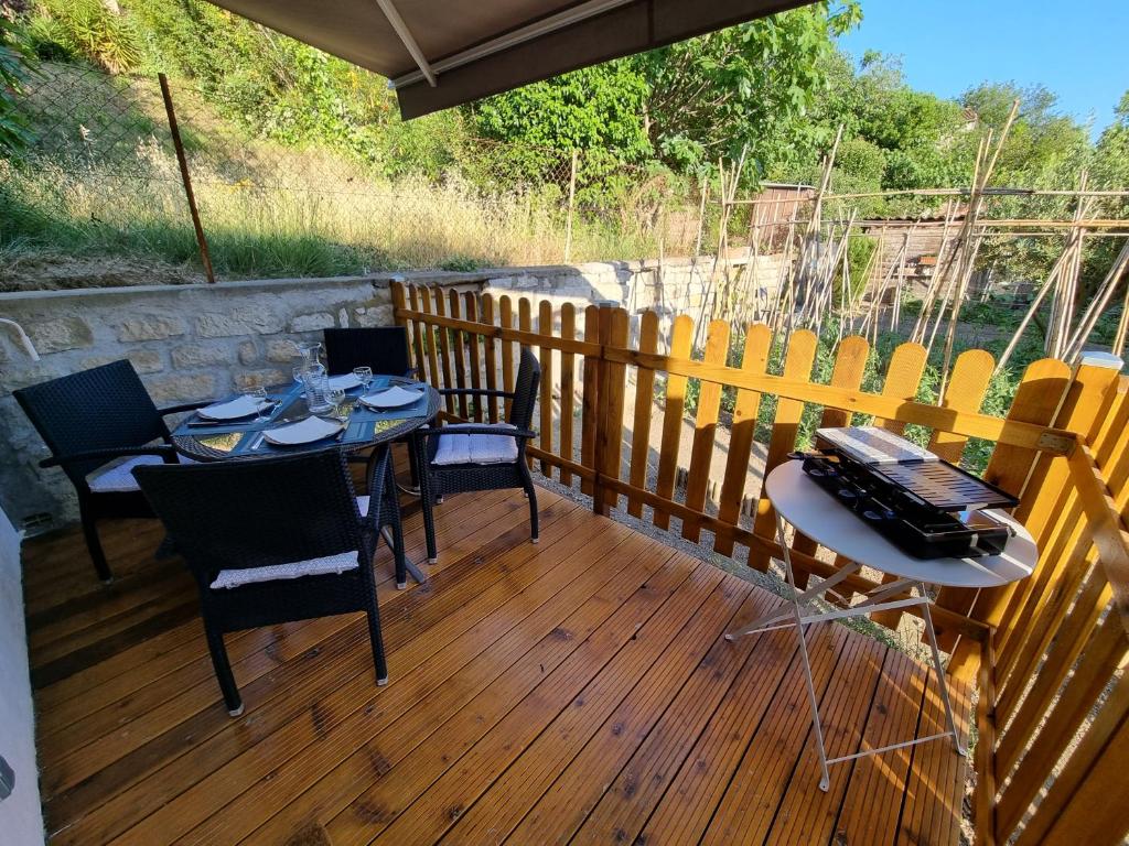 patio con tavolo e sedie su una terrazza in legno di La petite Luciole entre mer et montagne. a Cagnes-sur-Mer