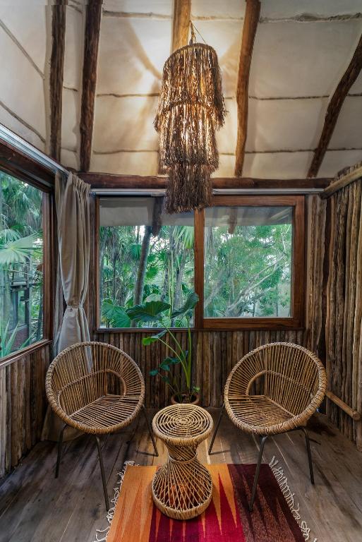 una stanza con tre sedie e un lampadario a braccio di Hidden Treehouse Tulum Eco-Hotel a Tulum