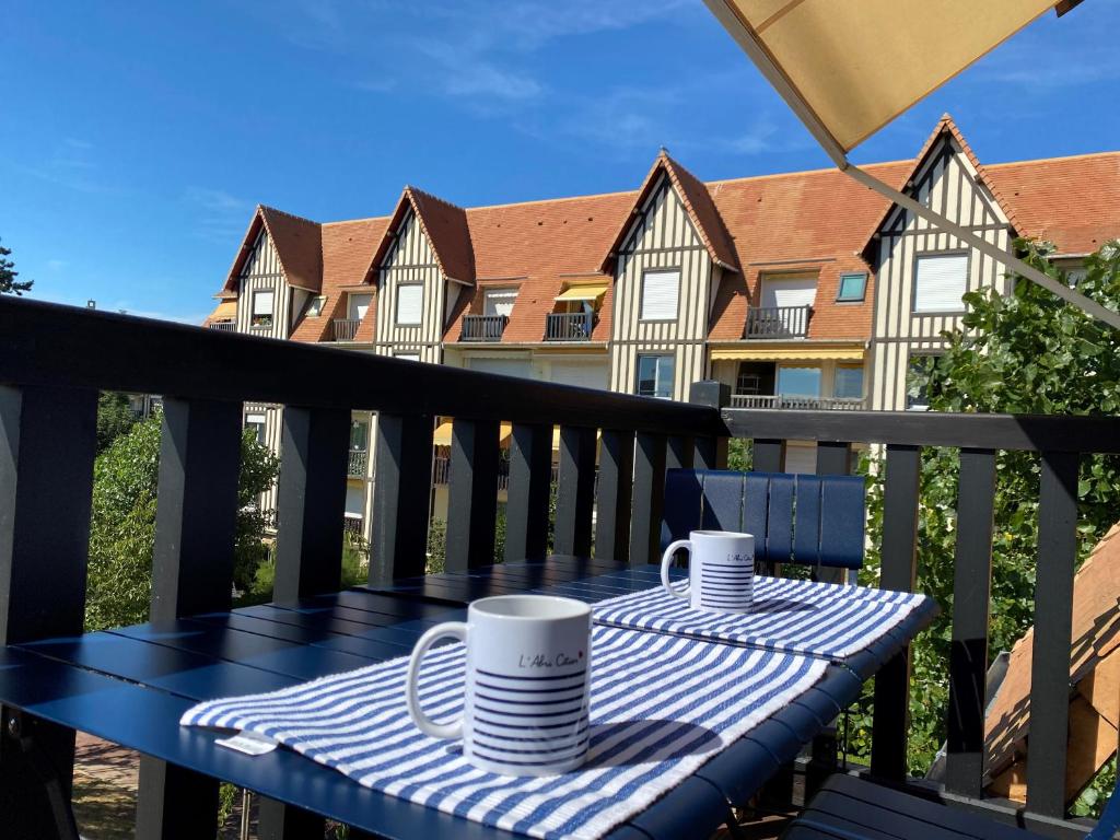 - une table sur un balcon avec deux tasses dans l'établissement Escapade marine à 'l'Abri Côtier', à Deauville