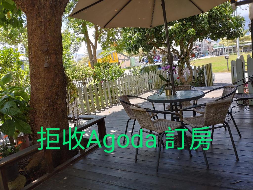 una mesa y sillas en una terraza de madera con sombrilla en 儷池2房2-5人包棟, en Chishang