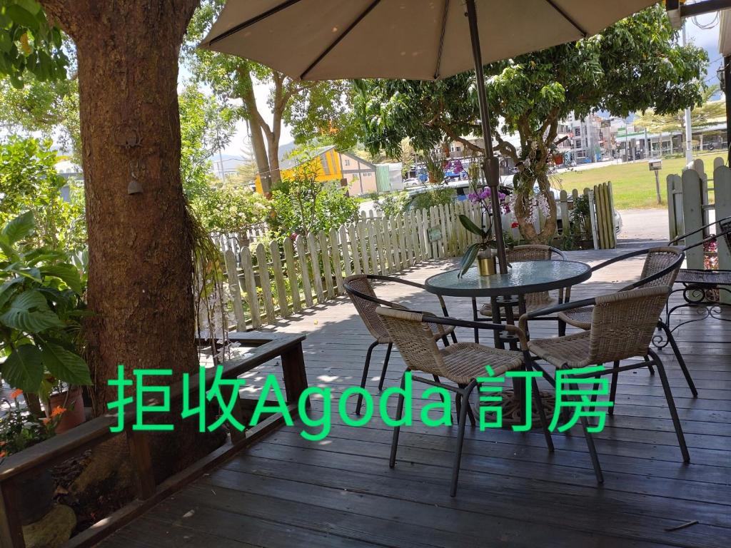 a table and chairs on a wooden deck with an umbrella at 儷池2房2-5人包棟 in Chishang