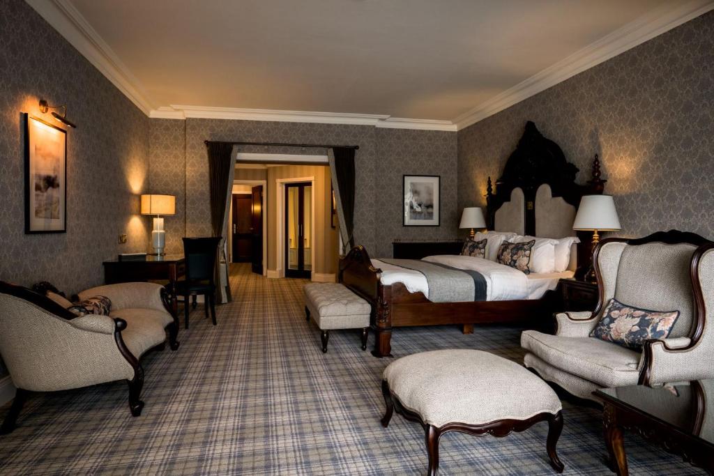 a bedroom with two beds and chairs and a desk at Harvey's Point in Donegal