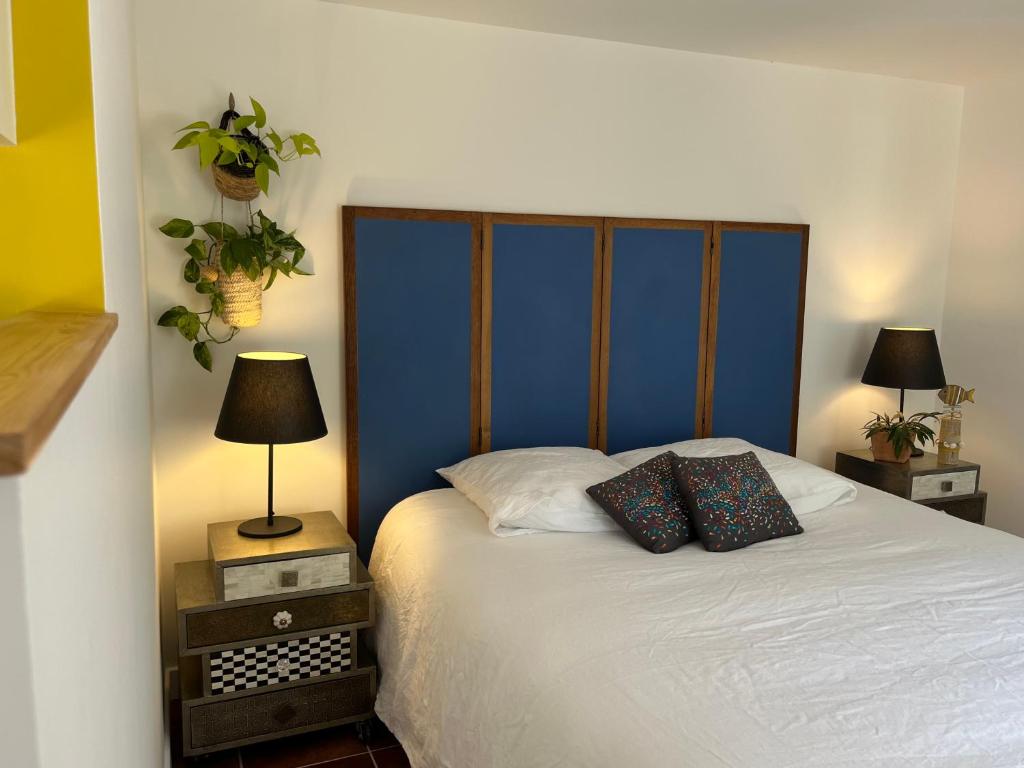 a bedroom with a bed with a blue headboard and two lamps at Gîte cosy sur jardin in Moëlan-sur-Mer