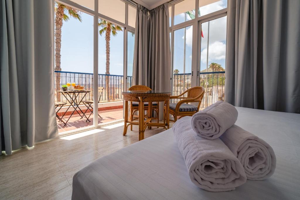 a bedroom with a bed and a balcony with a table at Hotel Don Ignacio in San José