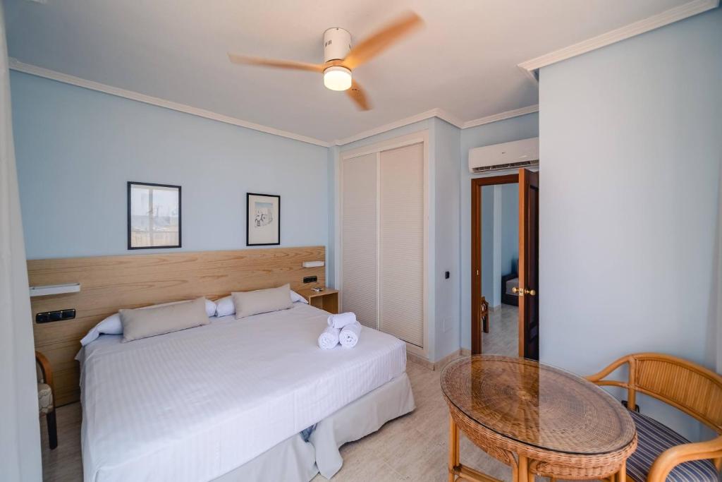 a bedroom with a white bed and a table at Hotel Don Ignacio in San José