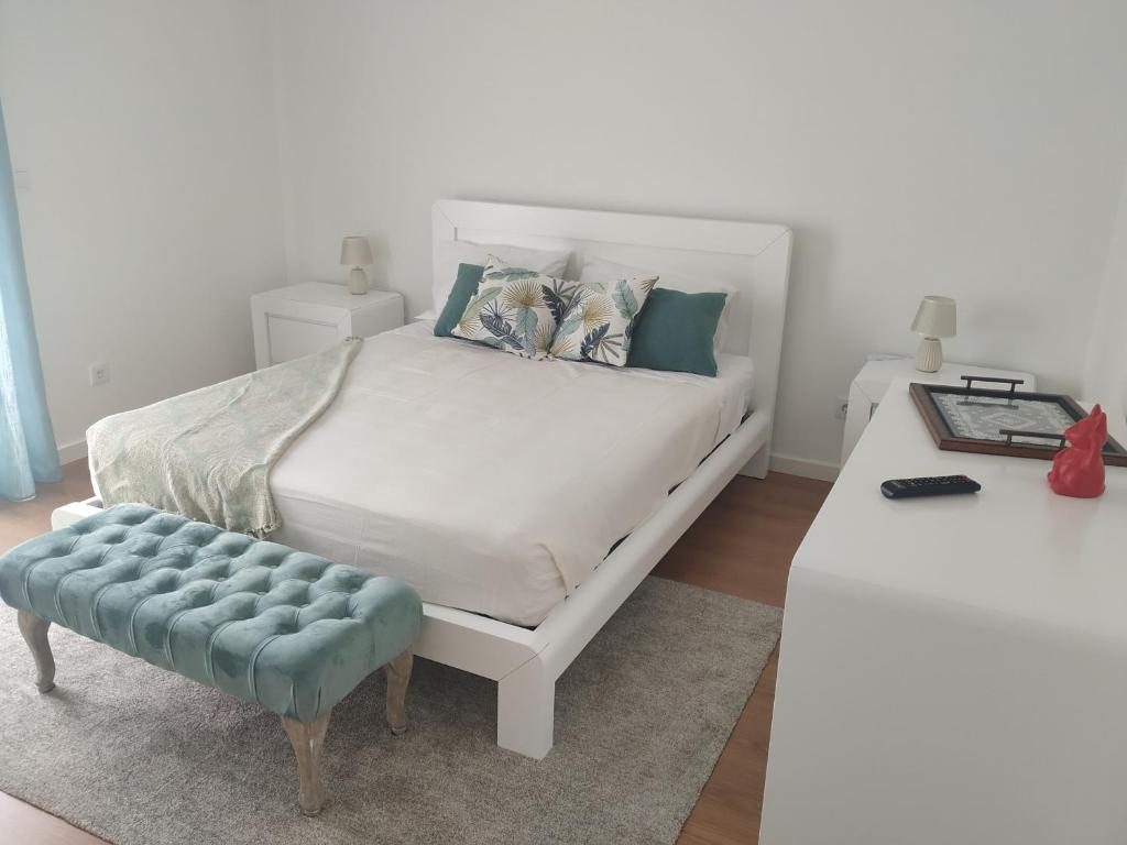 una camera con un letto bianco e uno sgabello blu di Brava a Vila Franca do Campo
