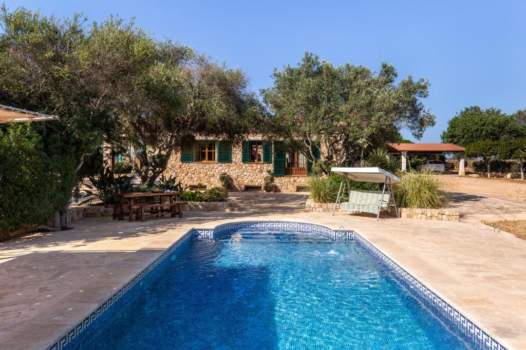 a swimming pool in front of a house at Finca Es Turo in Santanyi