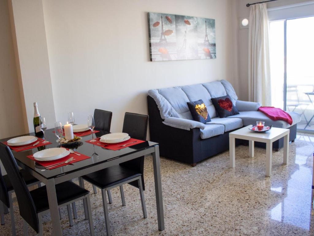 a living room with a table and a blue couch at Puesta de Sol Rentals 3AJ in Playa de San Juan