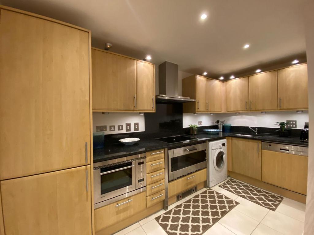 a kitchen with wooden cabinets and a dishwasher at Fabulous 2 bed apartment in Vauxhall in London