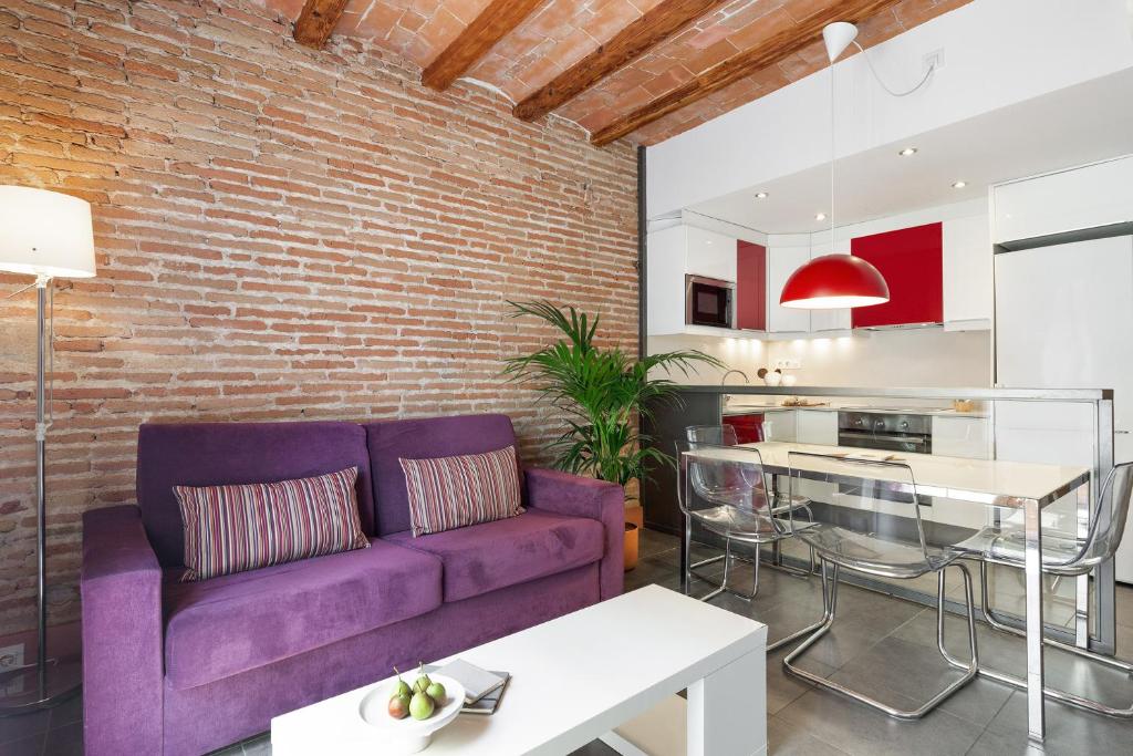 een woonkamer met een paarse bank en een bakstenen muur bij Ola Living MACBA in Barcelona