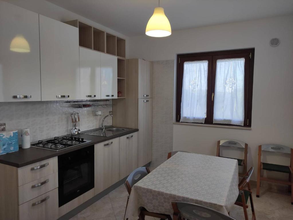a kitchen with white cabinets and a table and a table and a window at Casa Vacanze Magnolia in Scanzano