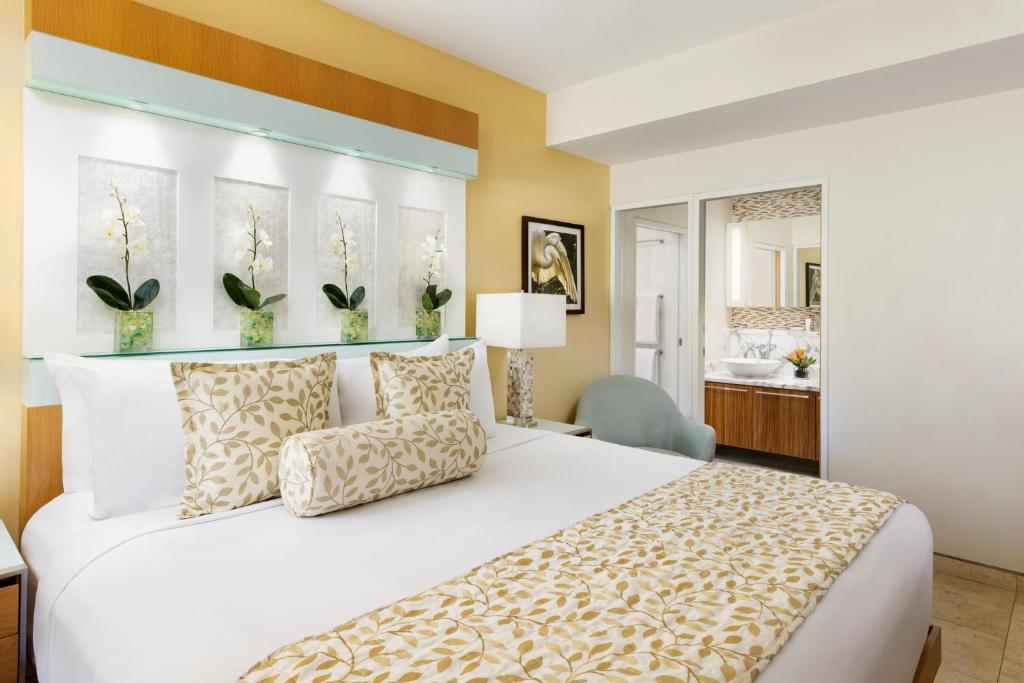 a bedroom with a large white bed and a bathroom at Santa Maria Suites Resort in Key West