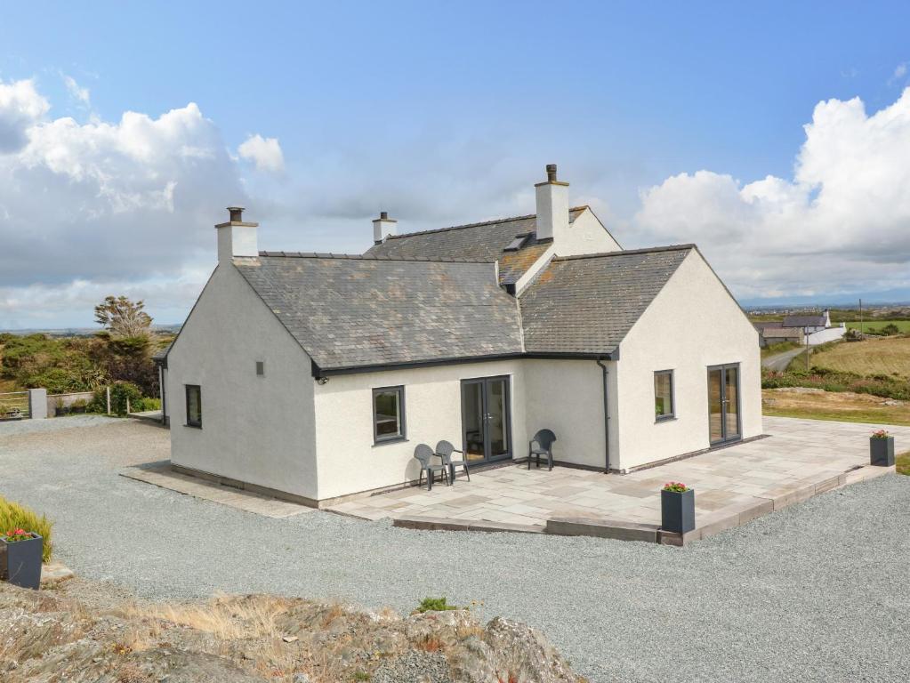 a white house with two chairs on a driveway at Bryn Meilw in Holyhead