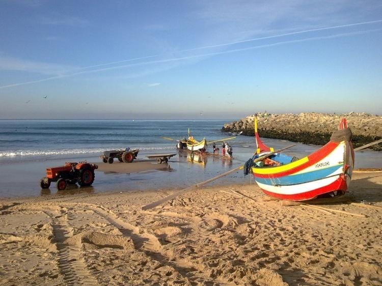 a boat on the beach with people in the water at Hotel Monte Lírio in Espinho