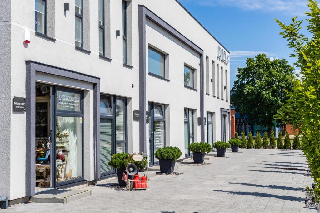 a white building with potted plants on a sidewalk at DO DOMIS LOFT PALANGA in Palanga