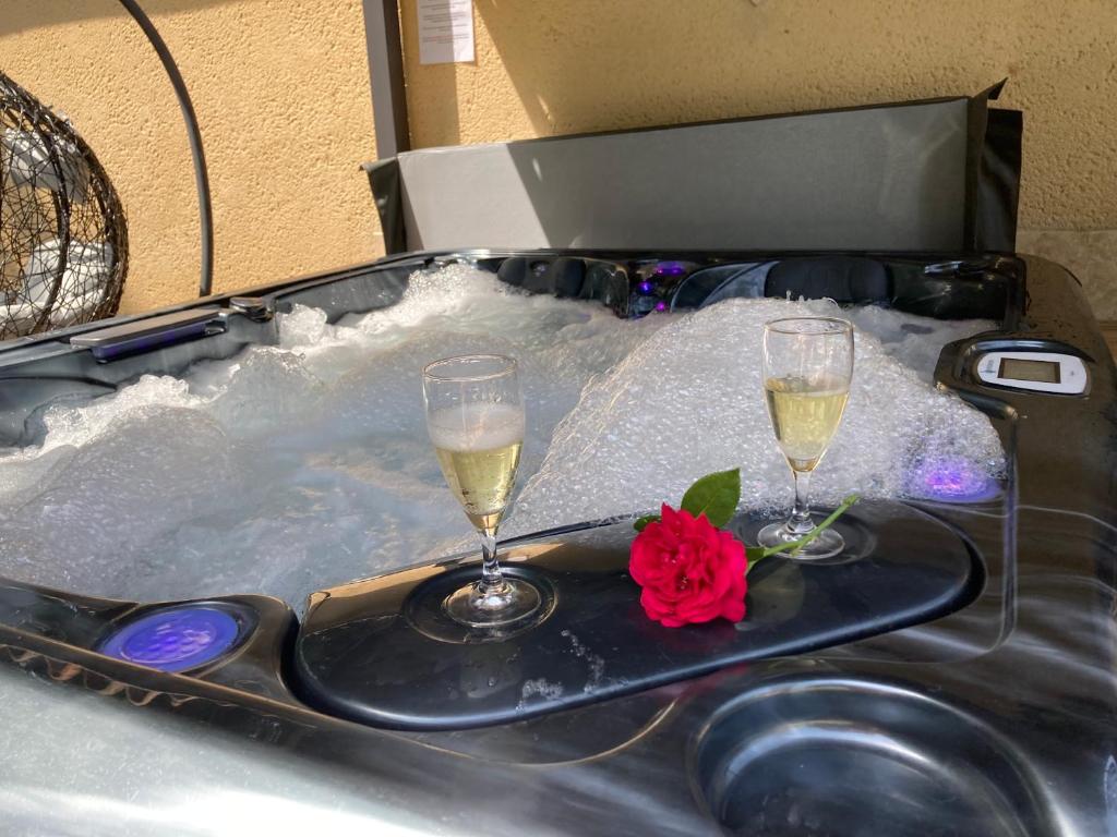 Gîte des Combes Blanches avec piscine et jacuzzi في Frayssinet-le-Gélat: كأسين من الشمبانيا وورد في حوض الاستحمام الساخن