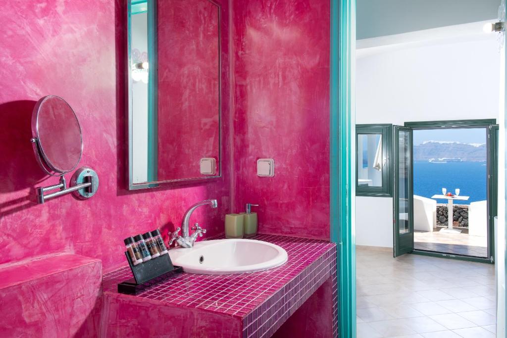 un bagno rosa con lavandino e specchio di Avant Garde Suites ad Akrotírion