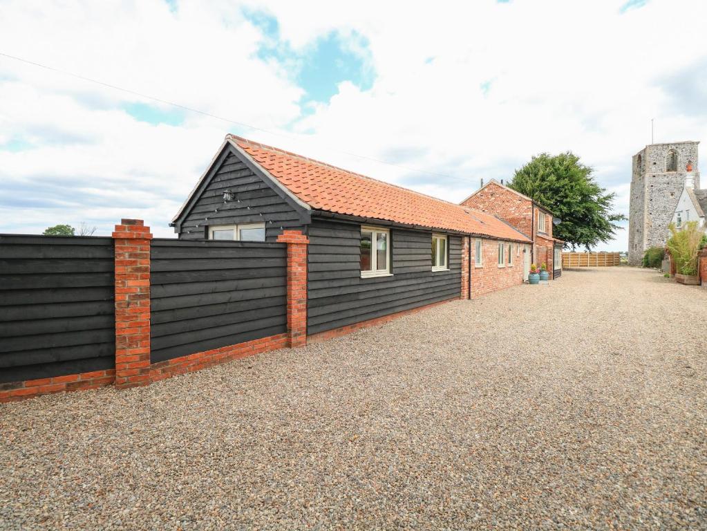 une maison avec une clôture noire à côté d'une allée. dans l'établissement Cobblers Barn, à Potter Heigham