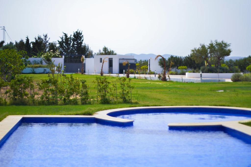 a swimming pool in a yard with a building in the background at Maison des Oliviers, Yasmine Hammamet, Bouficha in Hammamet Sud