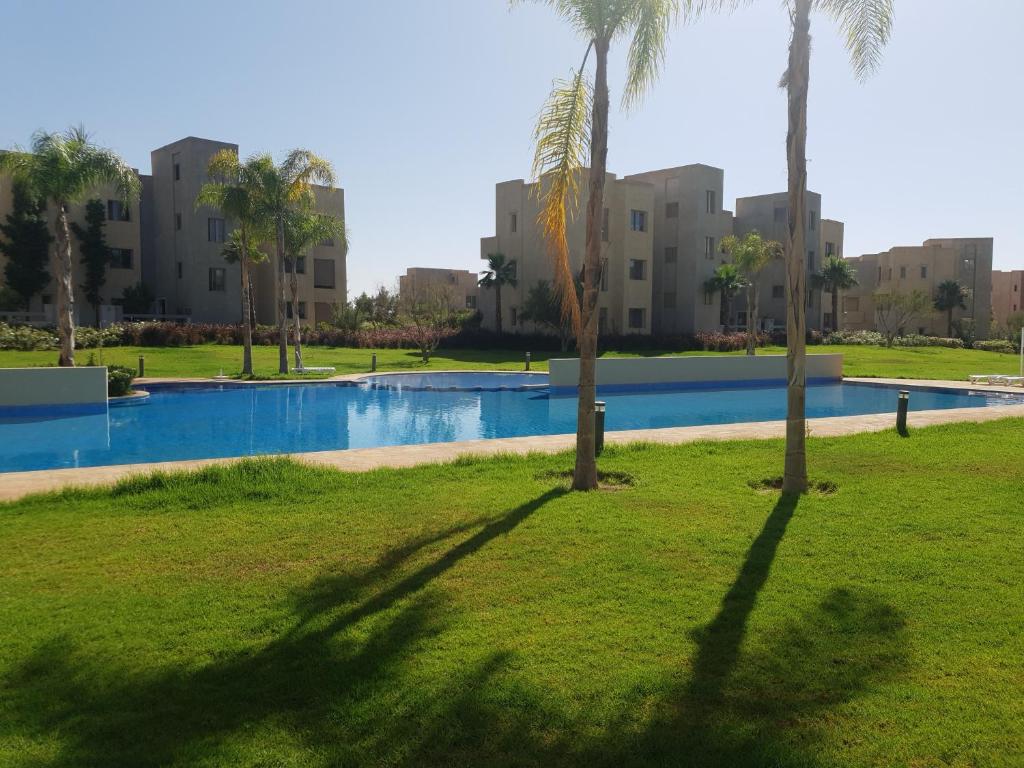 馬拉喀什的住宿－Superbe appart cosy résid privée avec piscine，游泳池旁棕榈树的阴影