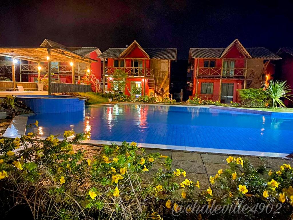 a swimming pool in front of a house at night at ChaleVille - Chalé 4902 in Luis Correia