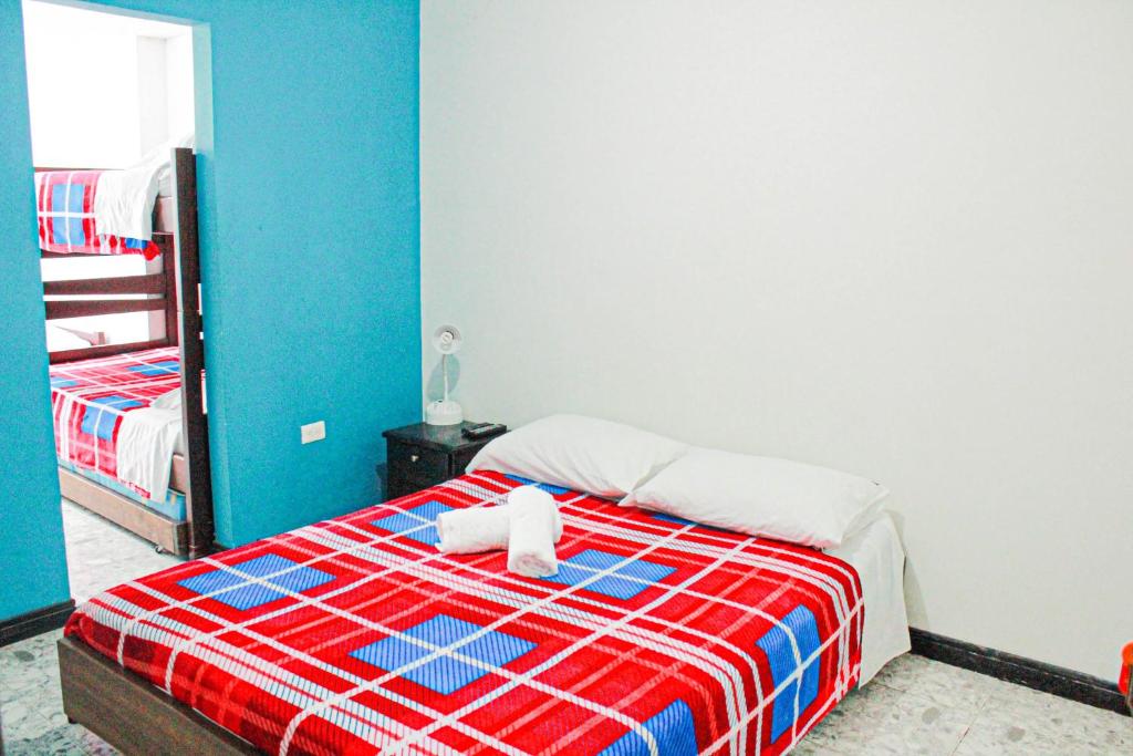 1 dormitorio con 1 cama con manta roja y azul en El Cable Hostal, en Manizales