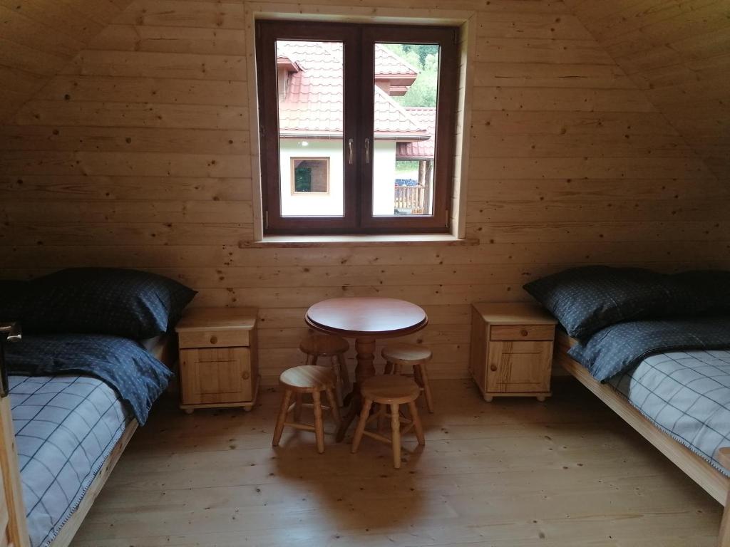 a room with two beds and a table and a window at Chatka pod Krzemienna in Cisna