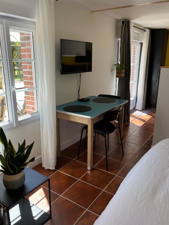 a room with a table and a tv and a bed at Gîte cosy sur jardin in Moëlan-sur-Mer
