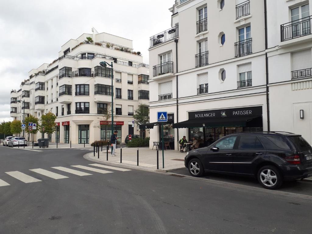 a black car parked in front of a building at Le Debussy 5 personnes, lit bébé, balcon, parking privé gratuit in Chessy