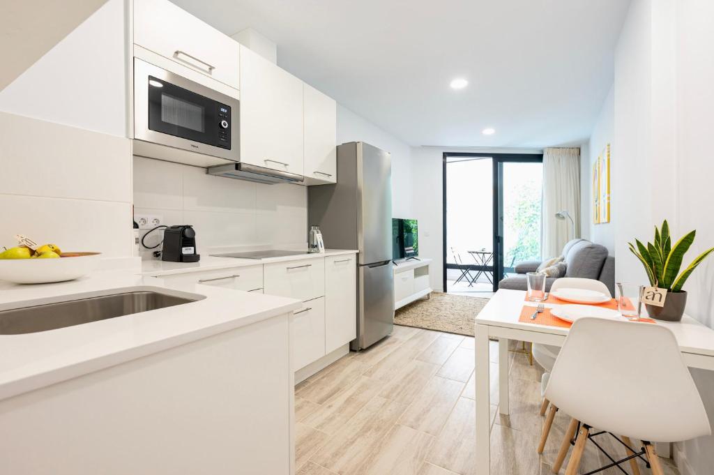 a white kitchen with a sink and a table at Famara Suites by AirNest in Las Palmas de Gran Canaria