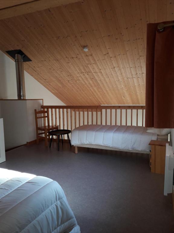 um quarto com 2 camas e um tecto de madeira em Chalet sur bord de l'eau em Nontron