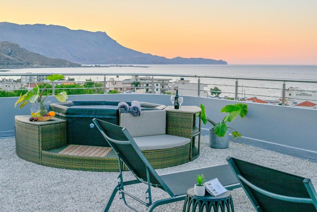 a patio with a hot tub and chairs on a balcony at Blue Horizon Kisamos Deluxe Apartment in Kissamos