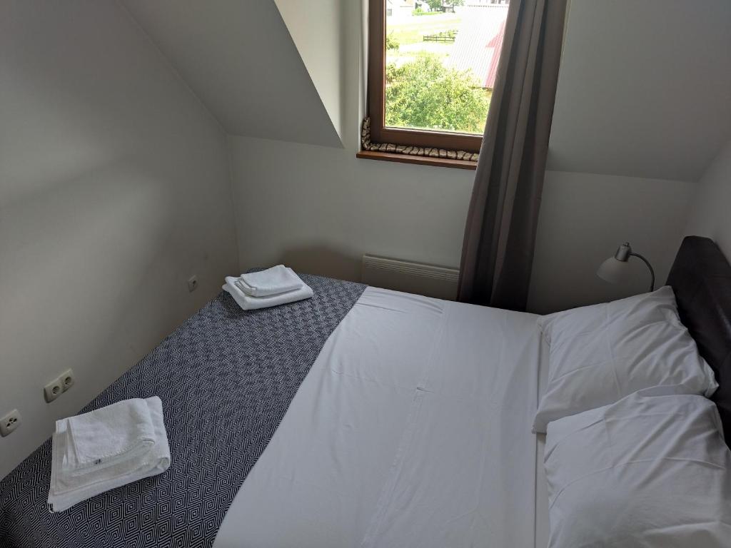 a bedroom with a bed with white sheets and a window at Apartman Ana in Mrkopalj