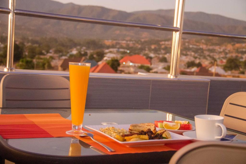 a table with a plate of food and a glass of orange juice at Airport View Hotel Songwe 