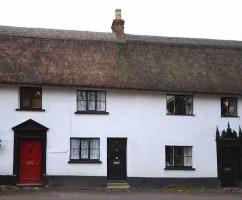 uma casa branca com uma porta vermelha e janelas em Thatched Cottage, beautiful village near the sea em Otterton