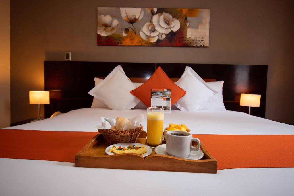 uma bandeja de comida e uma bebida numa cama em SM Hotel em Lima