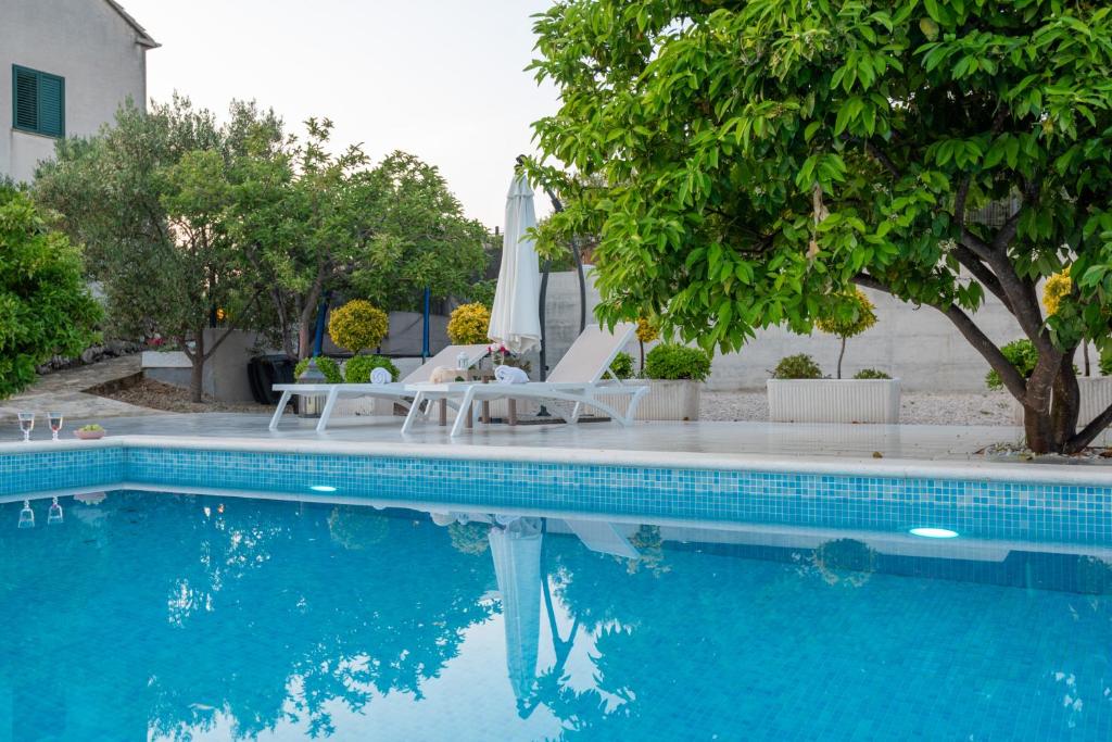 una piscina con sillas, una mesa y una sombrilla en Sun gardens, en Šibenik