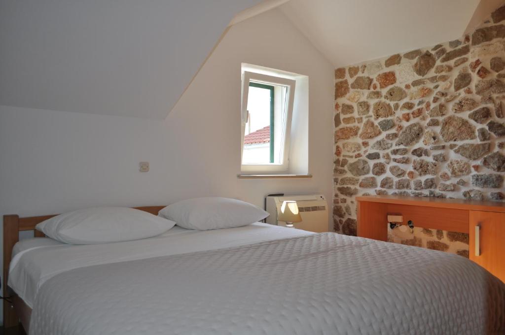 a bedroom with a white bed and a window at Dalmatian Villa Denis in Bol