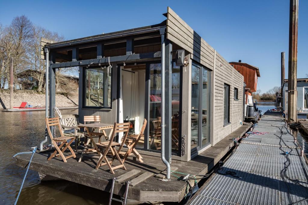 a house on a boat with chairs on a dock at Hausboot WILMA in Hamburg